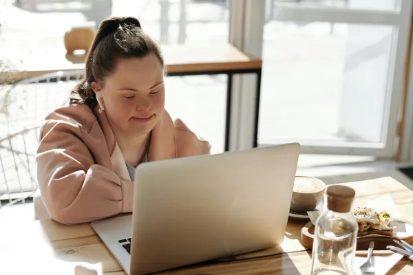 Young woman with a learning disability smiling while using a laptop.